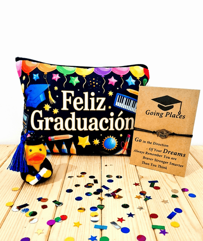 Conjunto de regalos de graduación compuesto por un pato de goma con birrete de borla azul y diploma enrrollado, a su lado una bolsa multiusos de color negro con dibujos multicolor y la frase "Feliz Graduación"a la derecha puede verse una pulsera de cordón negro con un dije de birrete presentada en tarjeta kraft con un texto emotivo. Todo sobre una superficie de madera clara con confeti metalizado de colores.