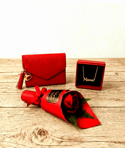 Monedero rojo, colgante dorado con la palabra Mamá y una Rosa Eterna roja sobre superficie de madera clara rustica. 