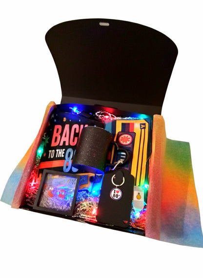 Caja de regalo negra con articulos y accesorios de diseño retro ochentero de colores fluor y luces led multicolor.