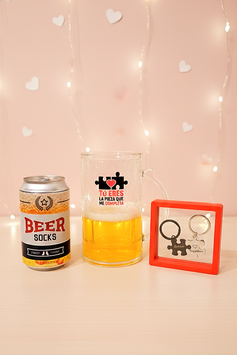 Los tres artículos de la BEERLY FIT BOX:  Una lata de Beer Socks, una jarra de cerveza enfriadora con el mensaje: Tu eres la pieza que me completa y un set de llaveros de piezas de puzzle
