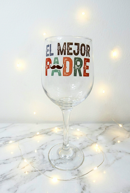 Primer plano de una copa de cristal personalizada con la frase "El Mejor Padre" sobre una superficie de mármol iluminada con luces led.