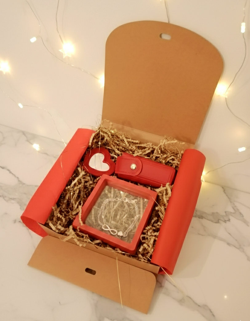 Caja de regalo Infini Red Box abierta con pulsera infinito, porta-labial rojo con espejo de corazon.