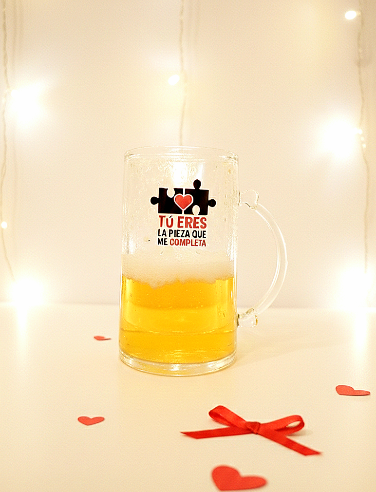 Detalle de una jarra de cerveza enfriadora, decorada con un diseño de piezas de puzzle con la frase "Tu eres la pieza que me completa"