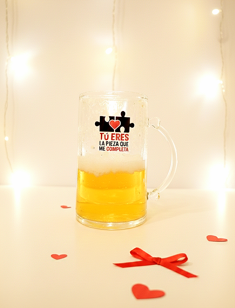 Detalle de una jarra de cerveza enfriadora, decorada con un diseño de piezas de puzzle con la frase "Tu eres la pieza que me completa"