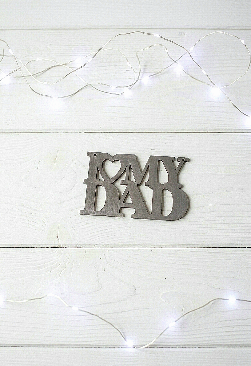 Letrero de madera en color gris metalizado "I love my dad" sobre fondo de madera blanco con luces led.