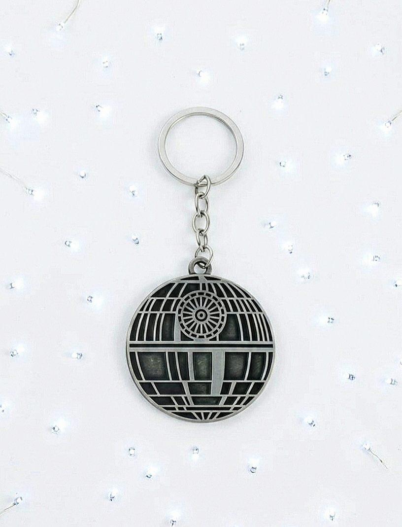 Llavero de metal con diseño de Estrella de la Muerte sobre un fondo blanco de luces led.