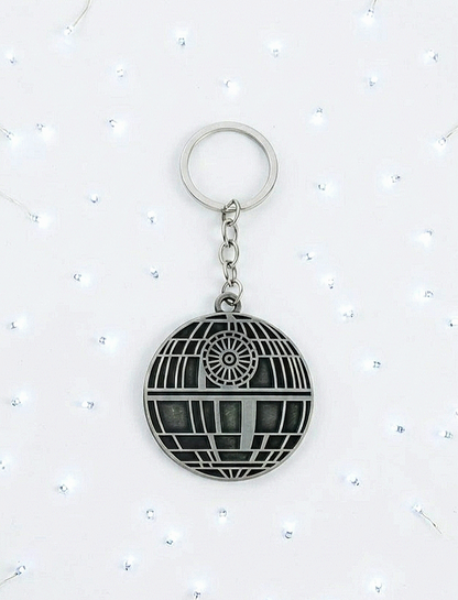 Llavero de metal con diseño de Estrella de la Muerte sobre un fondo blanco de luces led.
