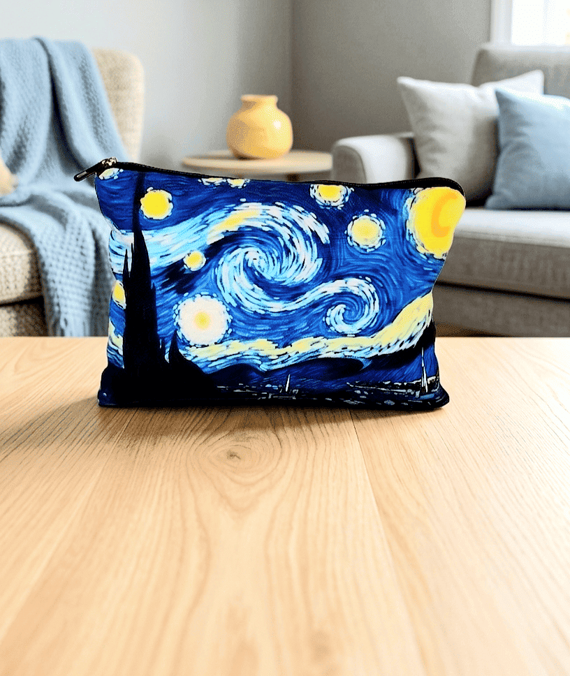 Neceser con cierre de cremallera con un diseño del cuadro de Van Gogh "La noche estrellada" sobre una superficie de madera clara y al fondo puede verse una sala de estar en colores claros y pastel.