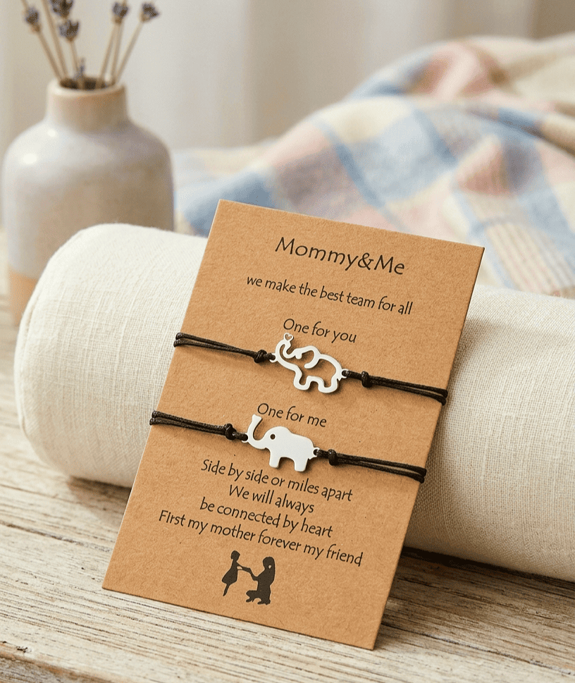 Primer plano detallado de una tarjeta kraft apoyada sobre un cilindro de tela de lino. La tarjeta contiene un texto en inglés con una ilustración. Sujetas a la tarjeta hay dos pulseras de cuerda negra ajustables con pequeños dijes de elefantes plateados. El dije superior es la silueta de un elefante y el inferior un elefante solido.