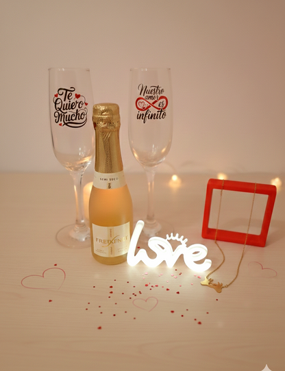 Botella de cava con dos copas personalizadas con frases romanticas en español  junto con luz led con la palabra LOVE y colgante dorado.