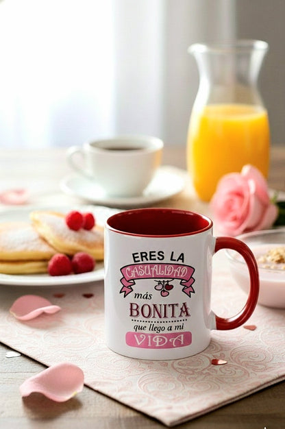 Taza de cerámica blanca con interior rojo y frase  "Eres la casualidad más bonita que llegó a mi vida" en fondo de desayuno romantico.